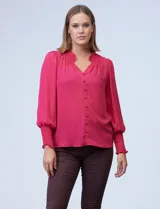 Blusa blanca de gasa con cuello a la base, escote en V y botones. Presenta punto smock en hombros y puños.