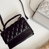 Cartera bandolera negra de ecocuero con diseño acolchado en rombos. Tiene asa corta superior y correa larga desmontable y regulable.
