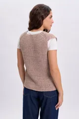 Chaleco de punto con lurex en color crudo, sin mangas, con escote en V y cierre frontal con botones.