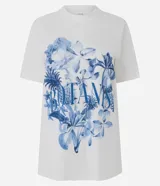 Remera de algodón blanca de corte largo, manga corta y cuello redondo. Presenta un gran estampado floral en tonos azules con la inscripción "Botanist" en el frente.