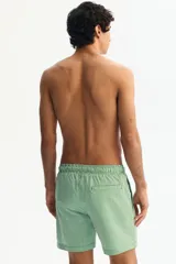 Short de baño a rayas verticales verdes y blancas, con cintura elástica y cordón de ajuste verde.