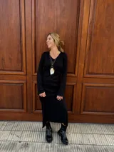 Vestido midi de color negro, confeccionado en tejido plisado con escote en V y mangas largas acampanadas.