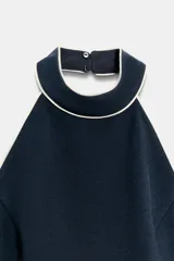 Top halter azul marino con detalles de ribetes en contraste color blanco en el cuello y el borde inferior, de diseño sin mangas y espalda descubierta con cierre de botones en el cuello.