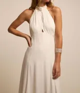 Vestido midi evasé color blanco, confeccionado en viscosa con foil. Presenta cuello halter trenzado, sisa americana y espalda descubierta.