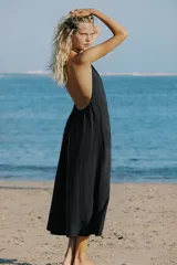 Vestido midi negro con cuello halter, lazada ajustable en el cuello y diseño fluido con espalda descubierta.
