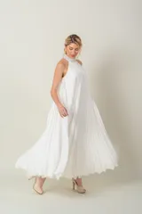 Vestido largo blanco de gasa plisada, sin mangas y con cuello halter bordado con perlas.