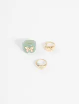 Set de tres anillos plateados, uno de plástico verde con una mariposa plateada, otro con forma de sello con una mariposa plateada y otro con forma de sello con un corazón plateado.