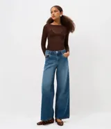 Pantalón de jean estilo wide leg con cintura media, cierre frontal con botón y bolsillos funcionales. Presenta un diseño de corte amplio y recto, con bordado de estrellas en los bolsillos traseros.