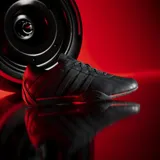 Championes urbanos Adidas Adiracer L en colaboración con Audi Revolut F1 Team, de color negro con detalles en rojo. Diseño de inspiración automovilística con las clásicas tres tiras en los laterales, suela de perfil bajo y el logo de la marca en la lengüeta y el talón.
