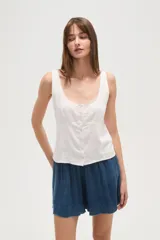 Musculosa blanca de viscosa con escote redondo, cierre frontal con botones y detalles bordados en los hombros.