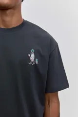 Remera de algodón color gris oscuro, de corte holgado y manga corta, con un pequeño estampado gráfico en el pecho.