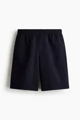 Short de felpa interlock color negro, de corte relajado a la rodilla, con cintura elástica con cordón ajustable oculto y bolsillos laterales.