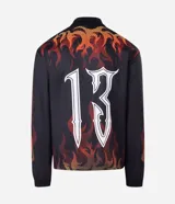 Remera de manga larga con corte boxy, confeccionada en microfibra de poliéster. Presenta un diseño estampado con motivos de llamas en tonos rojos y naranjas, junto con el número 13 en tipografía gótica en la espalda.
