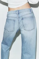 Jeans de tiro bajo con corte wide leg y largo cropped. Presenta diseño de cinco bolsillos, trabillas para cinturón y cierre frontal con cremallera y botón metálico.