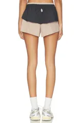 Short deportivo con diseño de doble capa, con capa interior en tono tostado y capa exterior negra con volado en la cintura, además de cordón ajustable blanco.