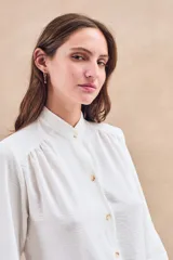 Blusa negra con cuello mao, calce al cuerpo y mangas 3/4 con puños abotonados. Cierre frontal con botones.