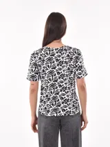Remera blanca con estampado animal print en negro, de corte recto y mangas cortas.