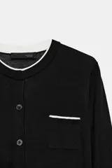 Chaqueta de punto de efecto doble capa color negro, con cuello redondo y ribete blanco, manga larga y cierre frontal con botones. Cuenta con un bolsillo de parche en el pecho con detalle en contraste.