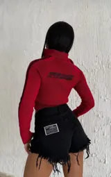 Short de jean negro de tiro alto, con ruedo deshilachado y etiqueta decorativa con texto en el bolsillo trasero.