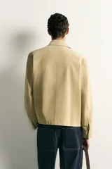 Cazadora regular fit de cuero con acabado de ante en color beige, con cuello solapa, bolsillos de plastrón en la cadera y cierre frontal de cremallera oculta por solapa con botones a presión.