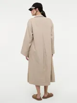 Vestido camisero oversized color beige, confeccionado en 83% ramié y 17% algodón, con mangas amplias, puños altos y cartera con botones delanteros.