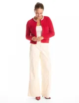 Chaqueta de tejido mohair color rojo, con cuello a la base decorado con bordado de perlas y canutillos. Presenta cierre frontal con broche interno, bolsillos simulados y detalles de apliques brillantes en los bordes.