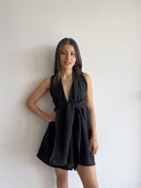 Vestido corto negro con escote halter y espalda descubierta. Presenta un corte a la cintura con falda acampanada.