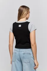 Musculosa de calce ajustado confeccionada en tejido acanalado, con escote redondo y detalle de puntilla en el escote y las sisas.