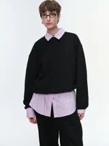 Buzo oversize de corte amplio y relajado, color negro, con cuello redondo acanalado, mangas largas anchas y bajo regulable con elásticos.