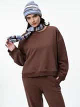 Buzo de cuello redondo y manga larga, con diseño oversize y corte relajado. Presenta puños y ruedo acanalados, confeccionado en tejido de textura suave.