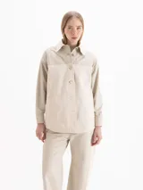 Camisa de manga larga color beige con diseño combinado, que incluye panel frontal de tejido texturizado, cuello clásico y cierre frontal de botones.