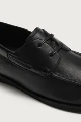 Zapato náutico de piel color negro con acabado abatanado, cordones de cuero y suela a tono.