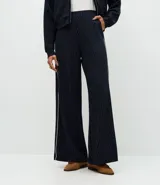 Pantalón wide leg de tiro medio, color azul marino con estampado de rayas diplomáticas blancas y detalle de piping lateral. Cuenta con cintura elástica y caída fluida.