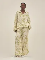 Conjunto de camisa y pantalón de lino color verde con estampado de flores blancas. La camisa es de manga larga y corte holgado.