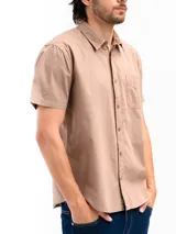 Camisa de manga corta color celeste claro, confeccionada en algodón, con cuello clásico y un bolsillo de parche en el lado izquierdo del pecho.