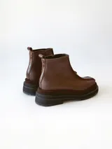 Bota corta de cuero en tonos chocolate, con diseño de paneles texturizados y suela track robusta de goma.