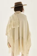 Ruana tejida en lana de cordero con diseño de sectores calados y terminación con flecos en los bordes.