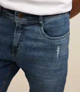 Pantalón de jean elastizado azul con lavado nevado, corte skinny y tiro medio.