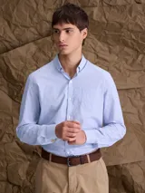 Camisa de manga larga en color celeste, con cuello button-down, cierre frontal de botones y bolsillo en el pecho.