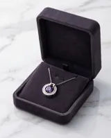 Collar de plata con cadena fina y dije circular que presenta una circonia central en color violeta rodeada por pequeñas piedras brillantes.