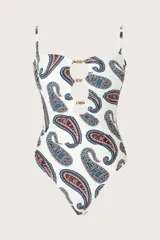 Malla enteriza de color blanco con estampado paisley en tonos azules, marrones y rojos. Presenta diseño bandeau con tirantes finos ajustables, escote con aberturas circulares unidas por argollas metálicas doradas.