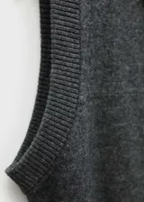 Chaleco de punto fino en color gris, con diseño recto, cuello camisero y cierre frontal parcial con botones. Sin mangas.