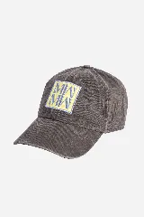 Gorra color gris con efecto acid wash, visera curva y parche frontal bordado con letras y diseño geométrico en tonos amarillo y celeste.