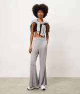 Pantalón deportivo femenino Get Over de corte flare, confeccionado en microfibra de color gris. Presenta cintura con pretina fija, diseño acampanado desde la rodilla y costuras decorativas frontales.
