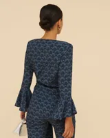 Blusa cruzada de manga larga con estampado geométrico en tonos azul y negro, escote en V y lazo lateral.