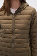 Campera acolchada tipo puffer, color beige claro, con capucha y cierre frontal. Presenta costuras horizontales y un calce entallado.