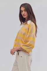 Remera tipo polo de algodón, de calce oversize, con diseño a rayas en tonos azul y celeste, cuello clásico blanco, botonadura corta, hombros caídos y mangas cortas.