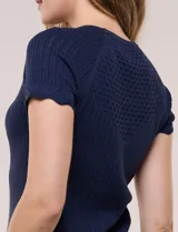 Blusa de punto calado color blanco, de silueta entallada, manga corta raglán y escote redondo, con detalles de tejido fantasía en el canesú y terminaciones festonadas.
