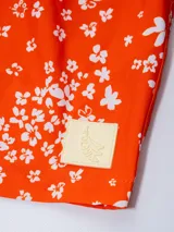 Short de baño rojo con estampado de flores blancas, cintura elástica con cordón ajustable, dos bolsillos laterales, un bolsillo trasero con cierre, suspensor de malla fina hipoalergénica y protección UV50.