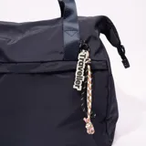 Bolso tipo tote azul marino con doble asa corta y dije colgante con la palabra "Traveller".